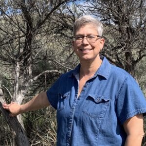 A person stands next to a tree