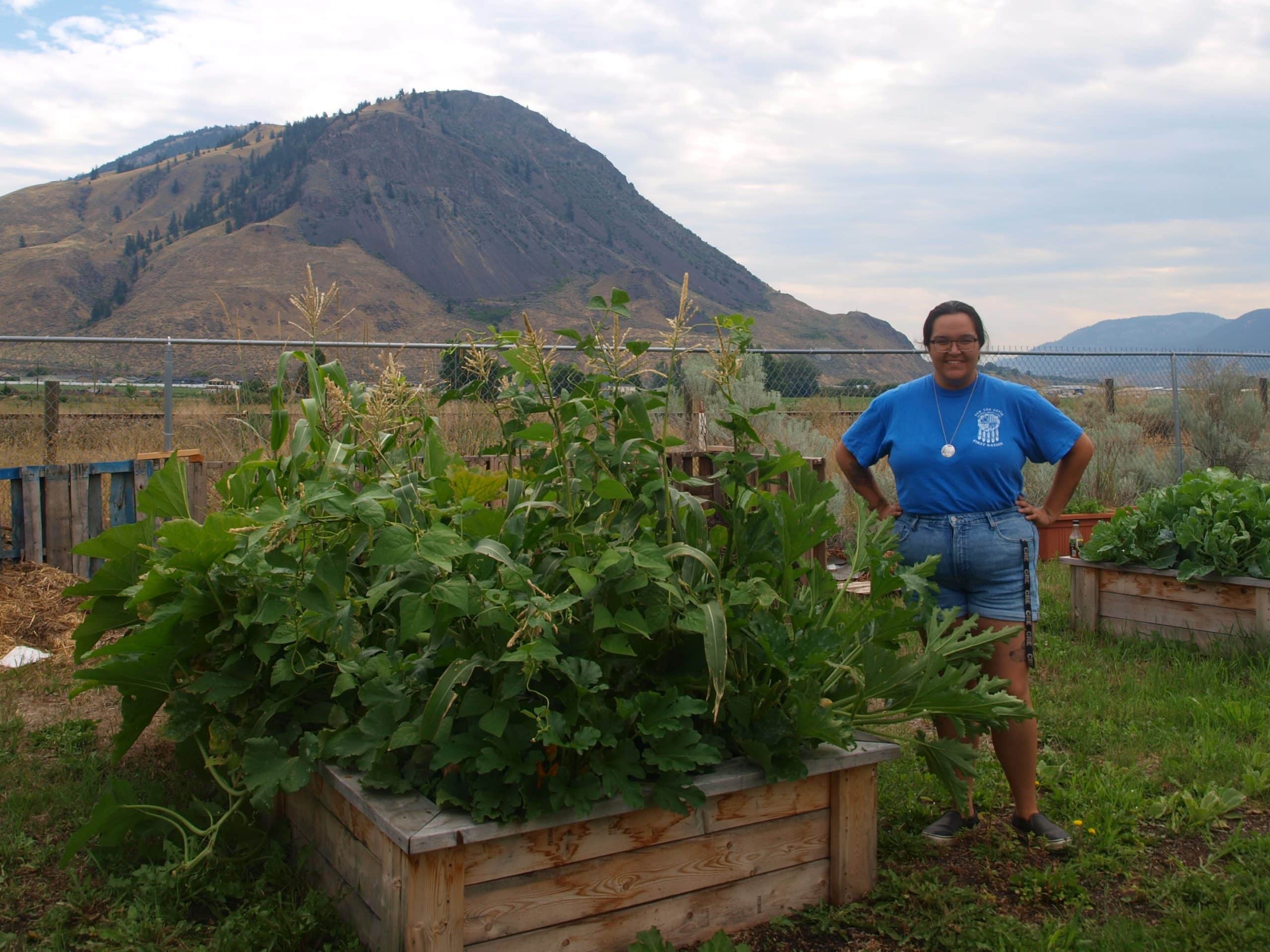 Horticulturist Shay Paul stands with a garden bed of the “Three Sisters” of American agriculture: corn, squash and beans.
