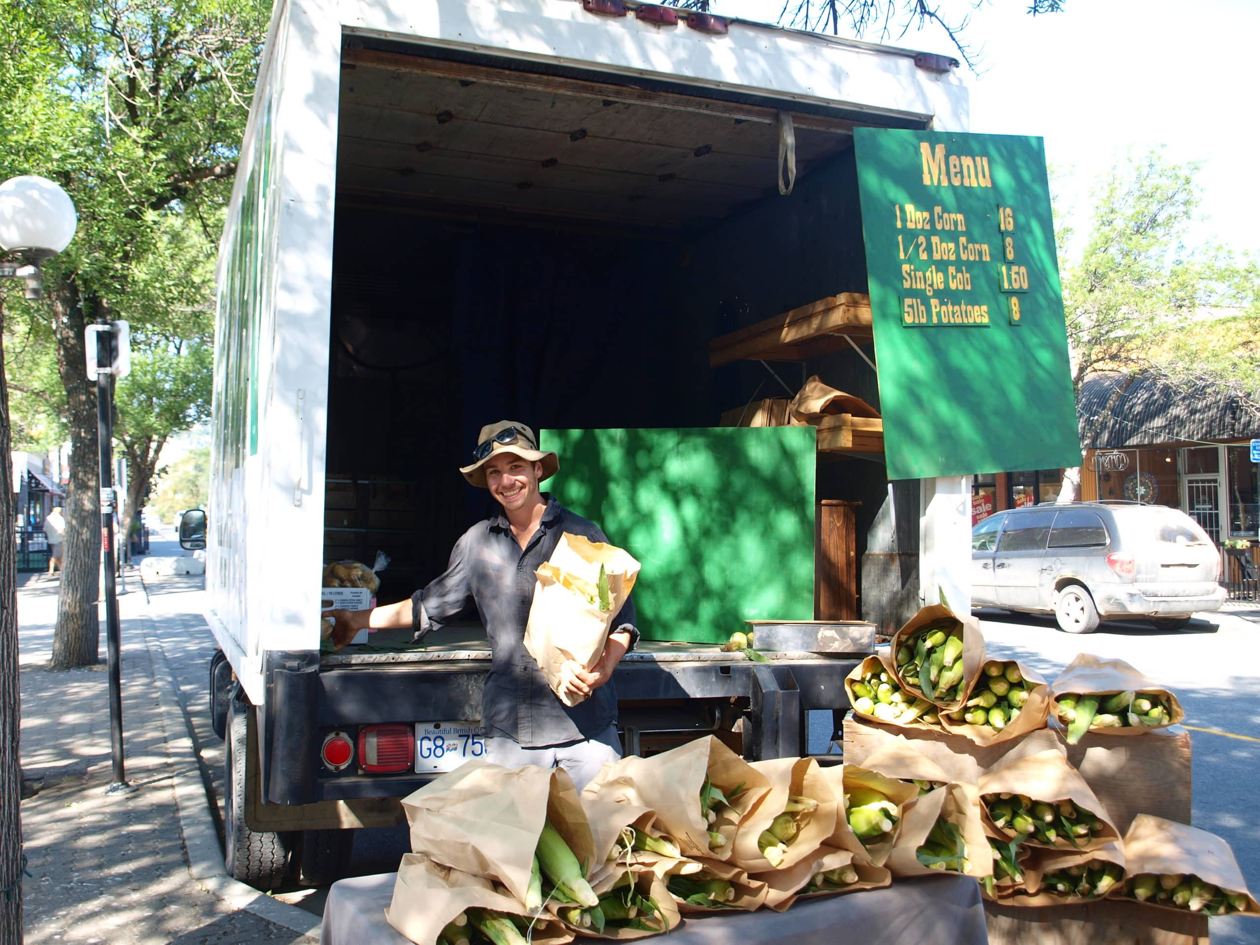 Lewis Burkholder of Burkholder Bros. Corn Farm smiles while stacking his product at the Wednesday market.