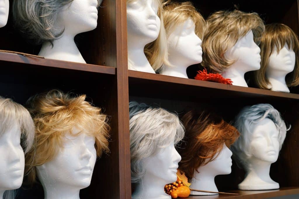 A variety of wigs in different cuts and colours sit on shelves.