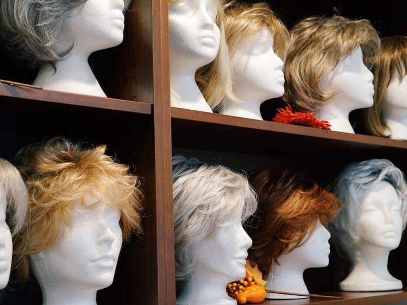 A variety of wigs in different cuts and colours sit on shelves.