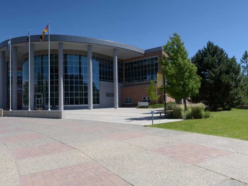 A concrete campus with greco roman pillars is shown on a sunny day.