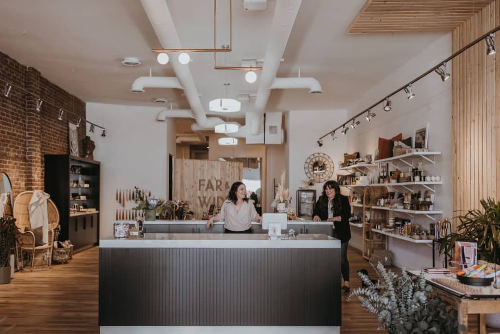 Two women stand inside Far & Wide, a Kamloops store. Shelves of products can be seen in the background.