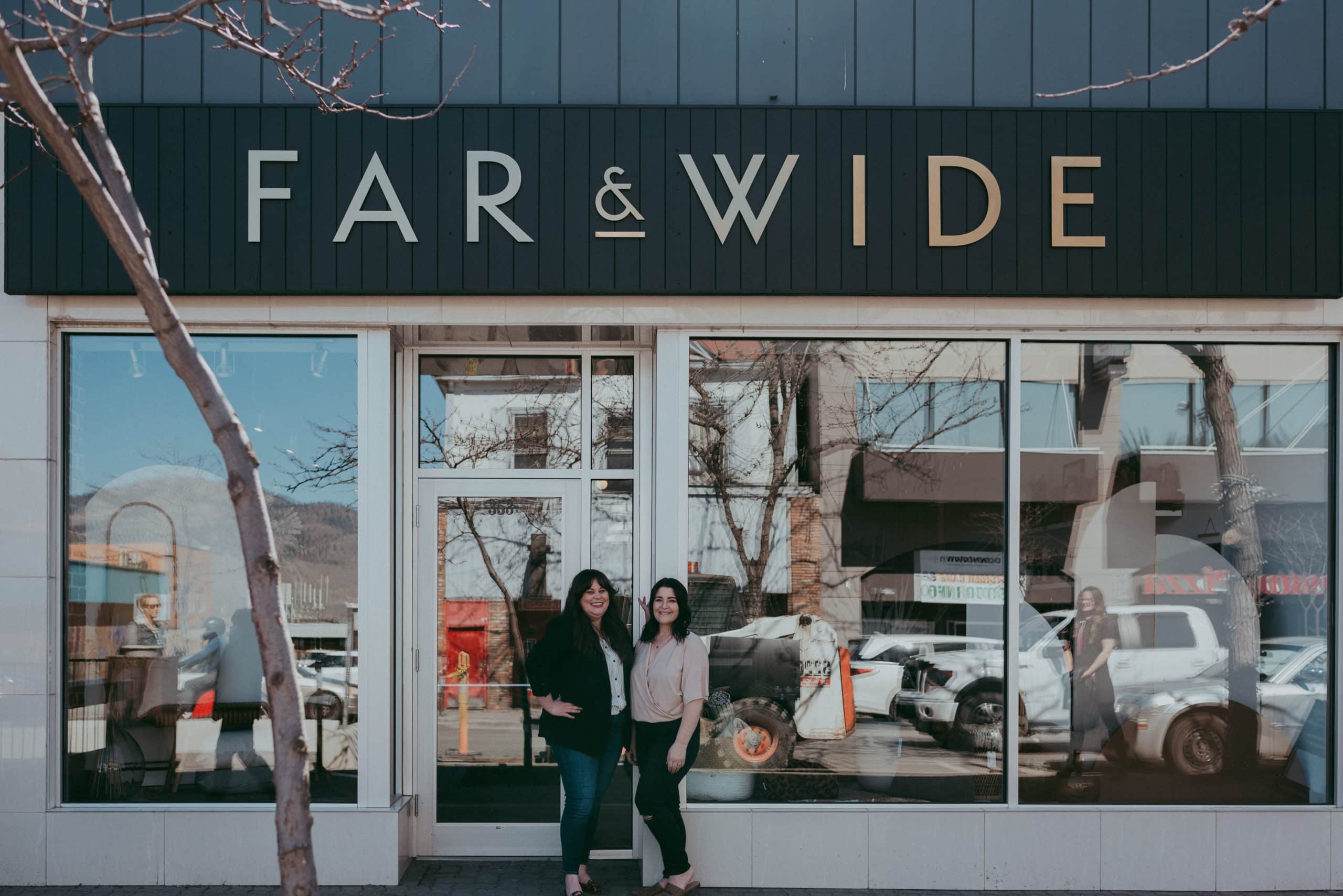 Calli Duncan and Brianne McDaniel stand outside of a storefront with the words "Far & Wide" on it.