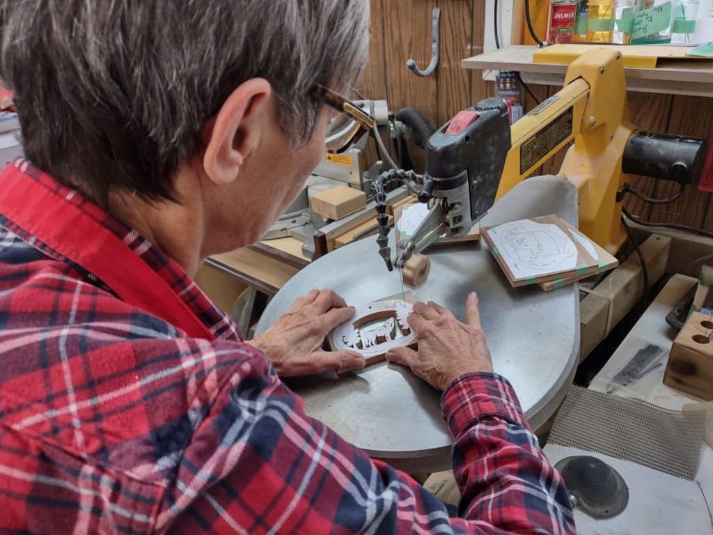 Hélène cuts a wolf design using a scroll saw