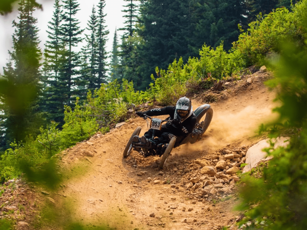 Landon McGauley turns a corner on a mountain bike trail in his three-wheeled adaptive bike, which allows him to sit while biking.