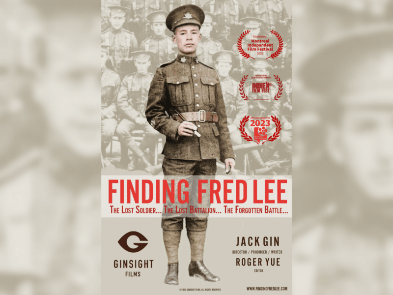 A Chinese man stands in his uniform. Poster is of 'Finding Fred Lee' documentary.