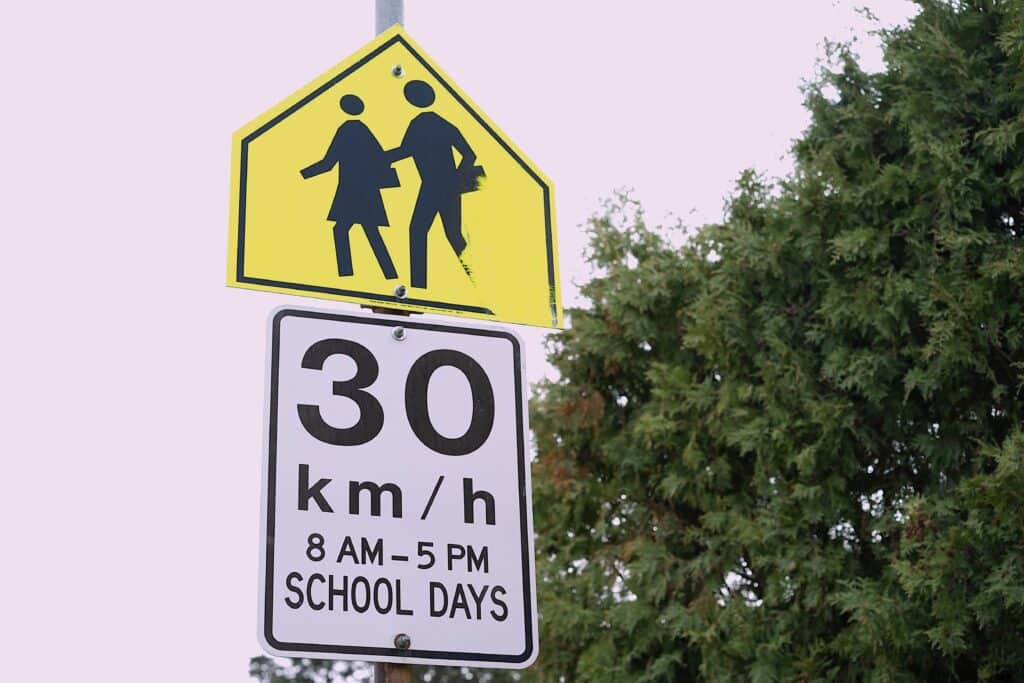 A school zone speed limit sign reads: 30 km/hr 8 AM - 5 PM SCHOOL DAYS.