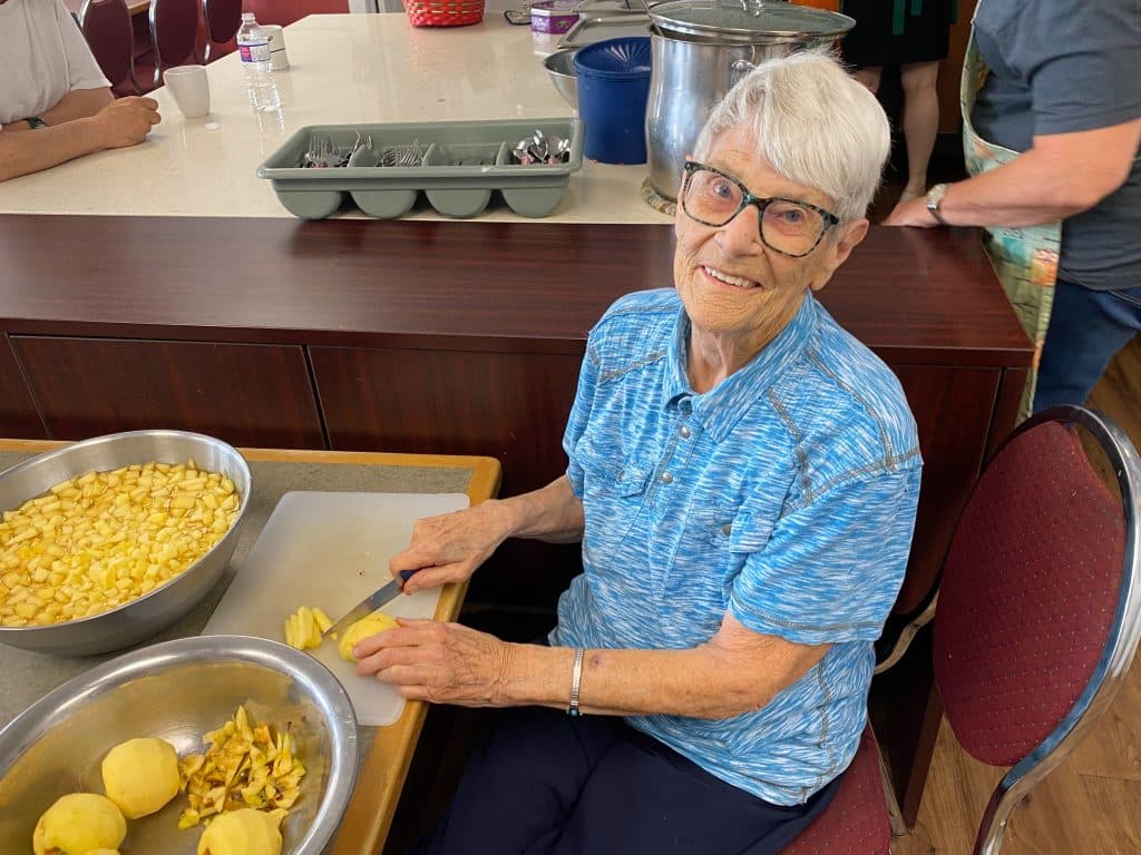 A volunteer in a blue shirt at The Loop cubes apples for an apple crumble served to folks who come in to eat and escape the heat at the resource centre.