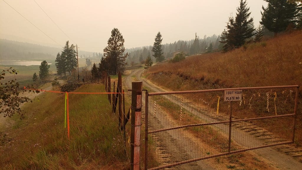 A gate blocks a road with eerie smoky skies in the background. The river can be seen in the distance.