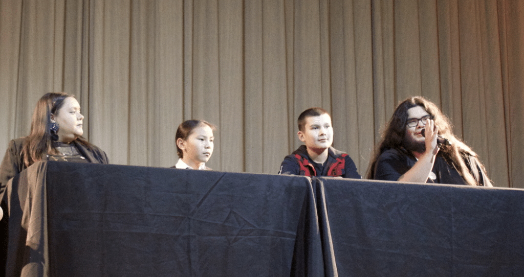 Four people sit behind a podium with microphones for the film panel.
