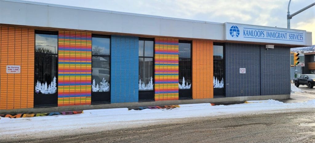 A building with colourful facade, blue and orange, stands in a grey day in Kamloops.