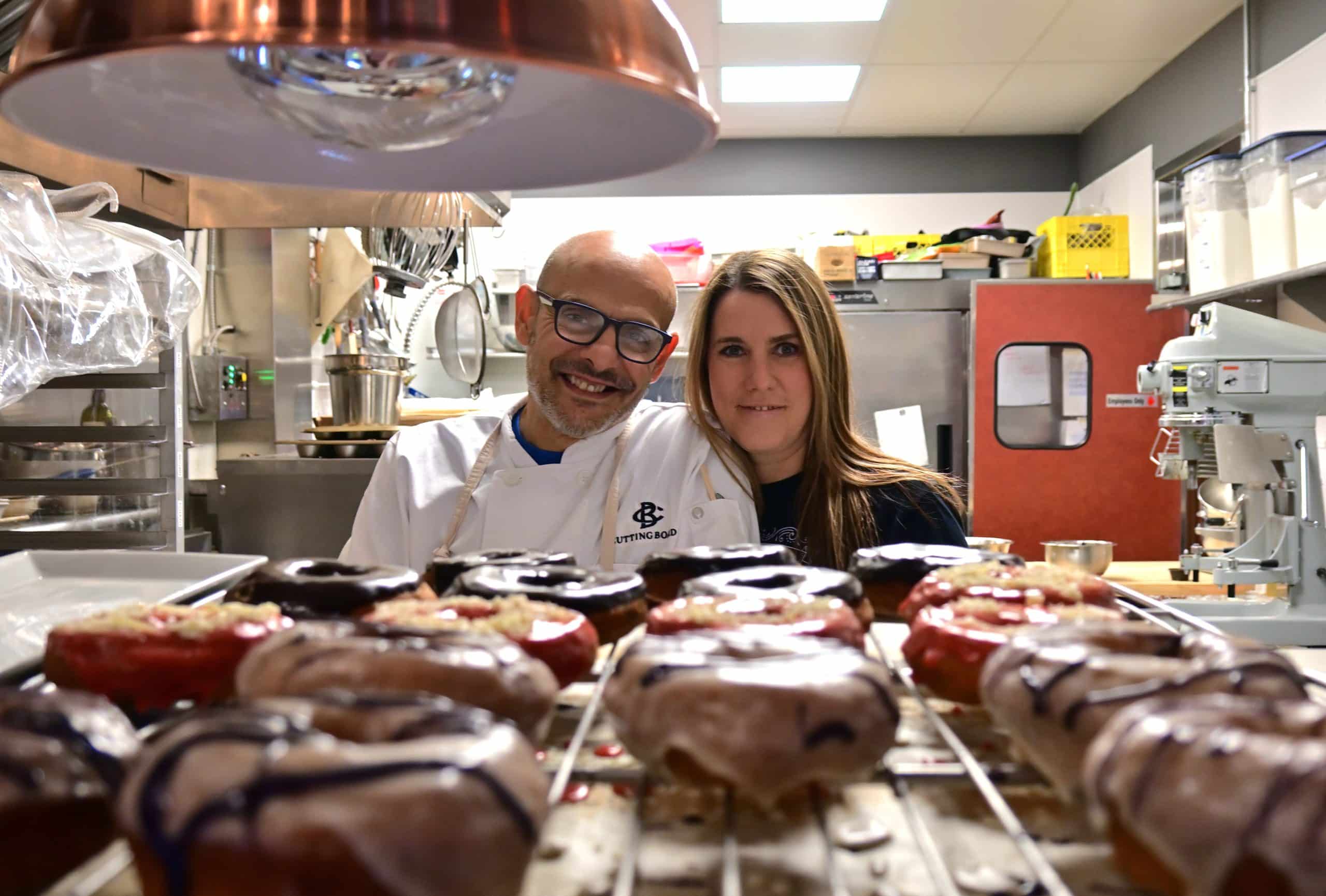 Marcus and Ashley Kharboutli look over a tray of fresh gluten-free doughnuts at Cutting Board Bistro