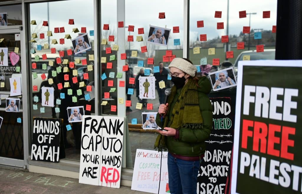 A speaker with Palestine Solidarity Kamloops stands amongst signs and post-its during the Feb. 21 protest. Photo by Lyssa Martin