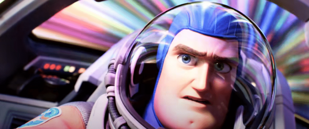 An animated still shows the domed-glass space helmet being worn by Buzz Lightyear. He is seated inside a space ship and a rainbow of color streaks through the window beside him as he shifts into light speed.