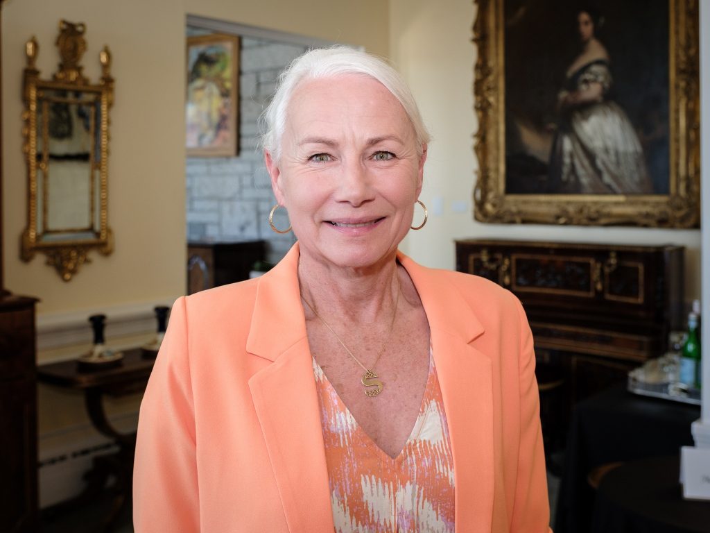 A woman in a peach blazer poses for a professional photo.