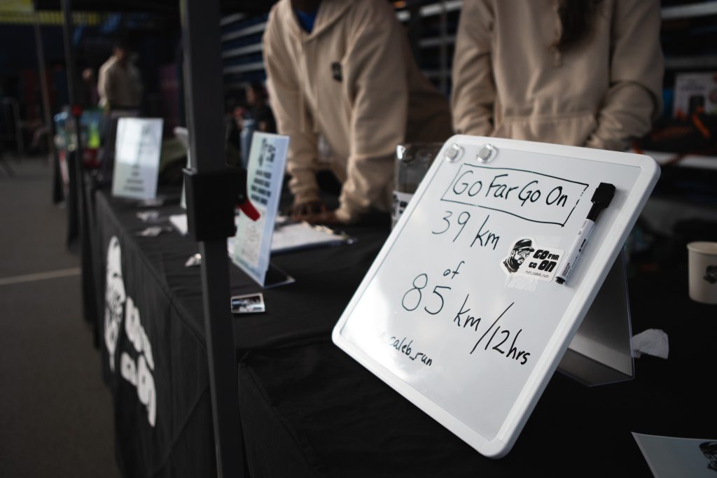 A small whiteboard on top of a table. The whiteboard reads "Go far go on. 39km of 85km/12hrs".