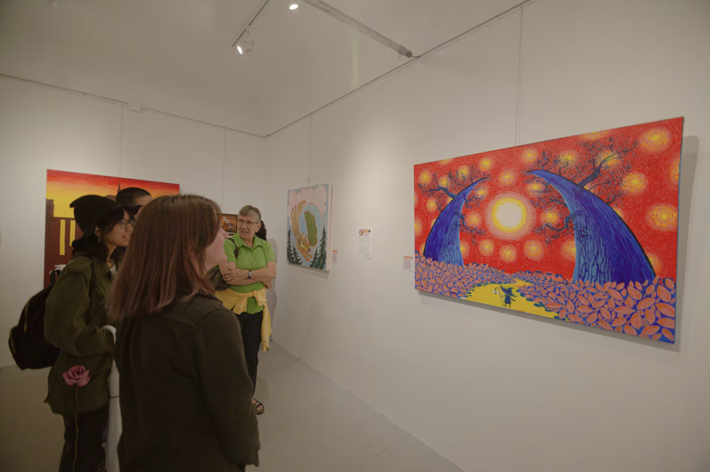 People are looking at a colorful painting at the exhibition. 
