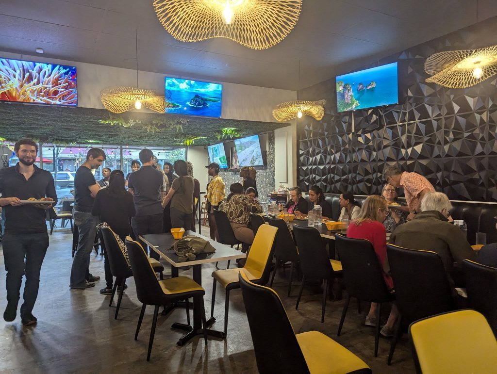 Some people are standing talking to each other at the dinner. Others are sitting and eating at the event organized by a Valid Dreams foundation. 